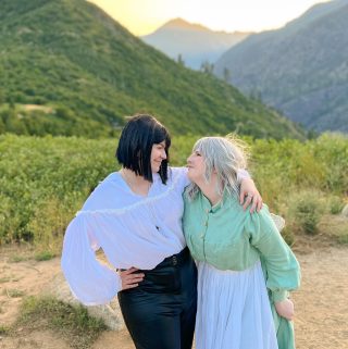 Nicole and Eli as Howl and Sophie gazing into each other eyes while standing in front of a mountain range and setting sun.