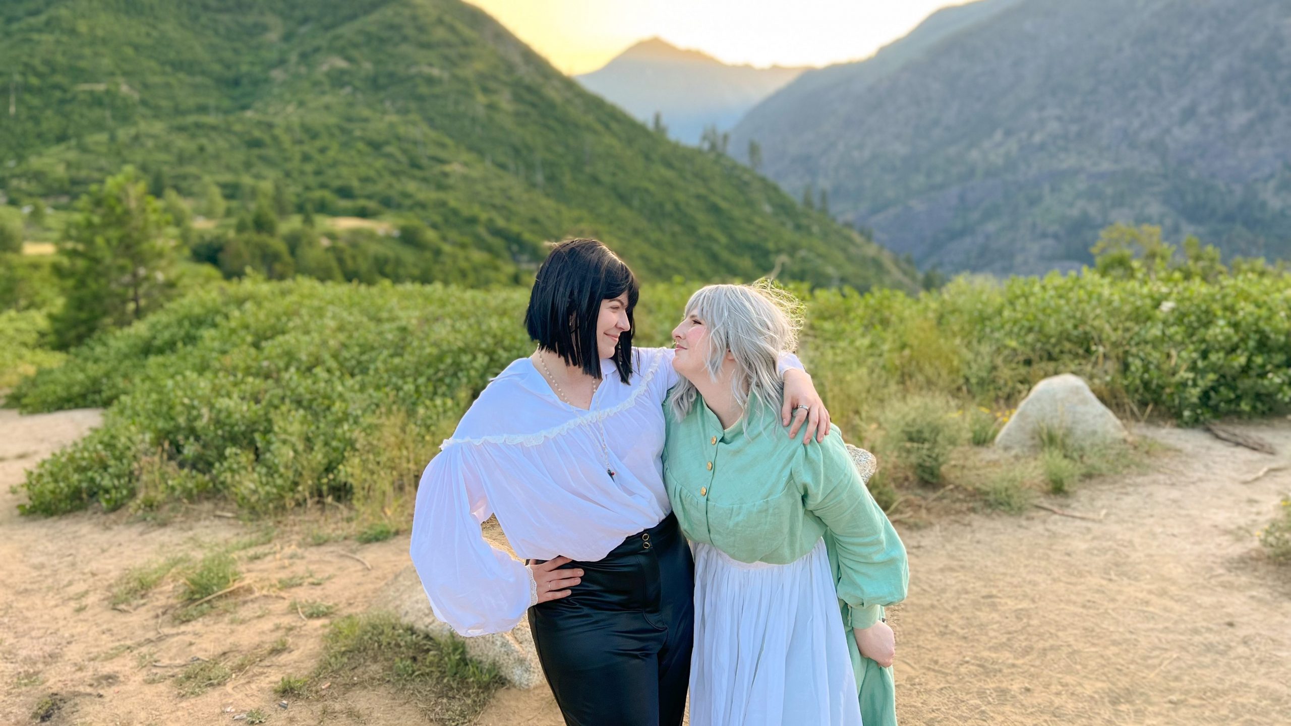 Nicole and Eli as Howl and Sophie gazing into each other eyes while standing in front of a mountain range and setting sun.